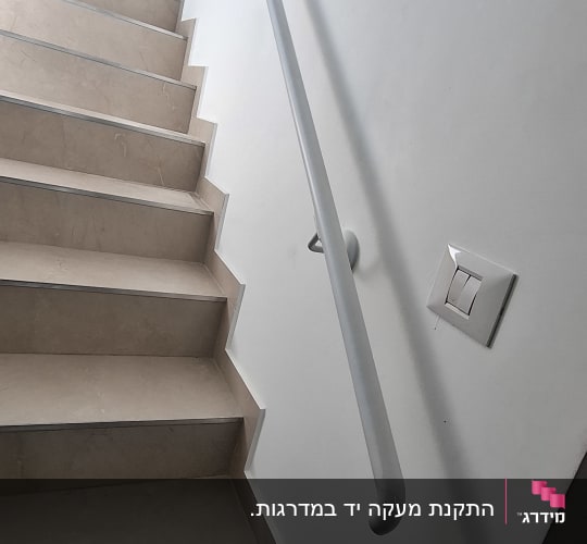 מעקה מתכת צמוד קיר בצבע לבן לאורך גרם מדרגות